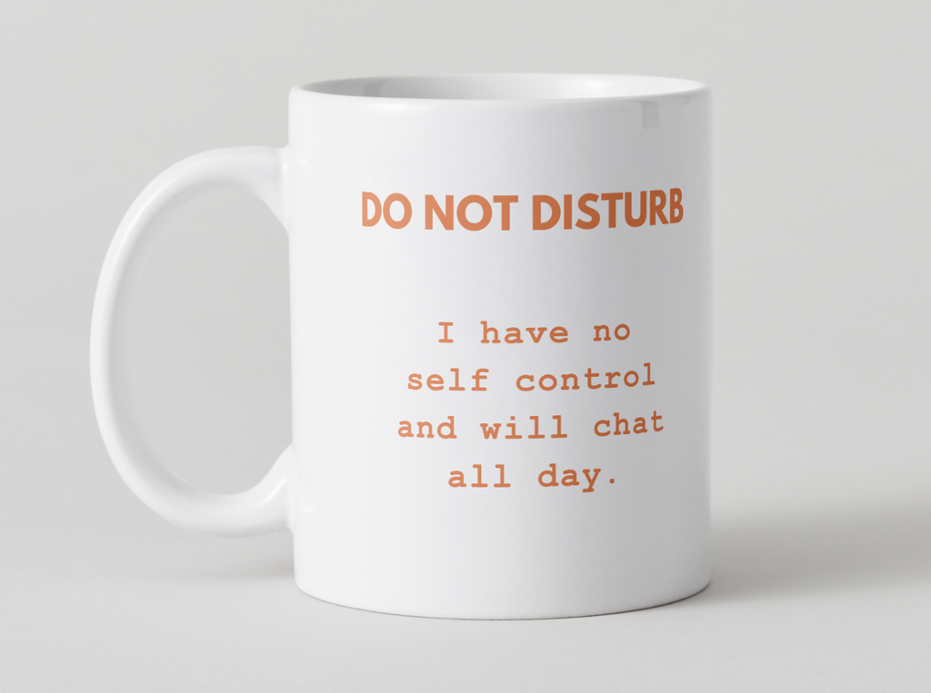 White mug with orange  'Do Not Disturb I have no self control and will chat all day.' design on a light gray 
