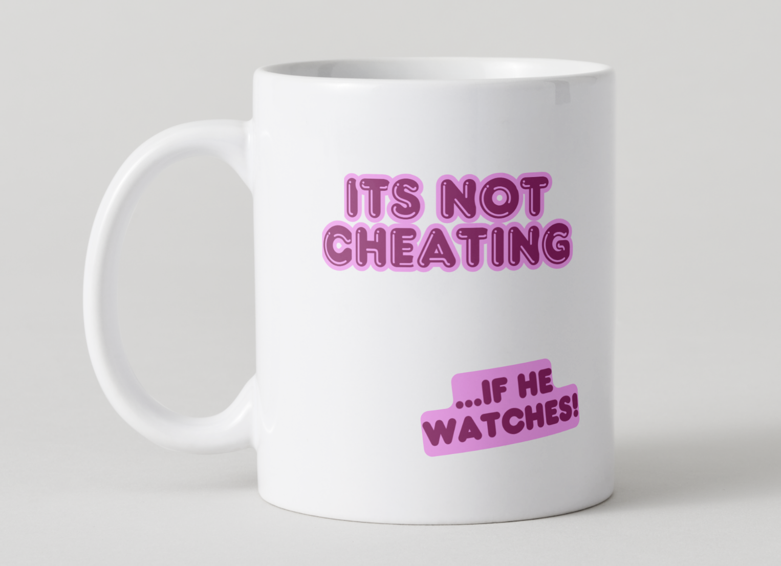 White mug with Pink 'It's not cheating ...if he watches' design on a light gray 