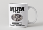 White mug with 'Mum to be loading... please wait' text and ultrasound image on a light gray background