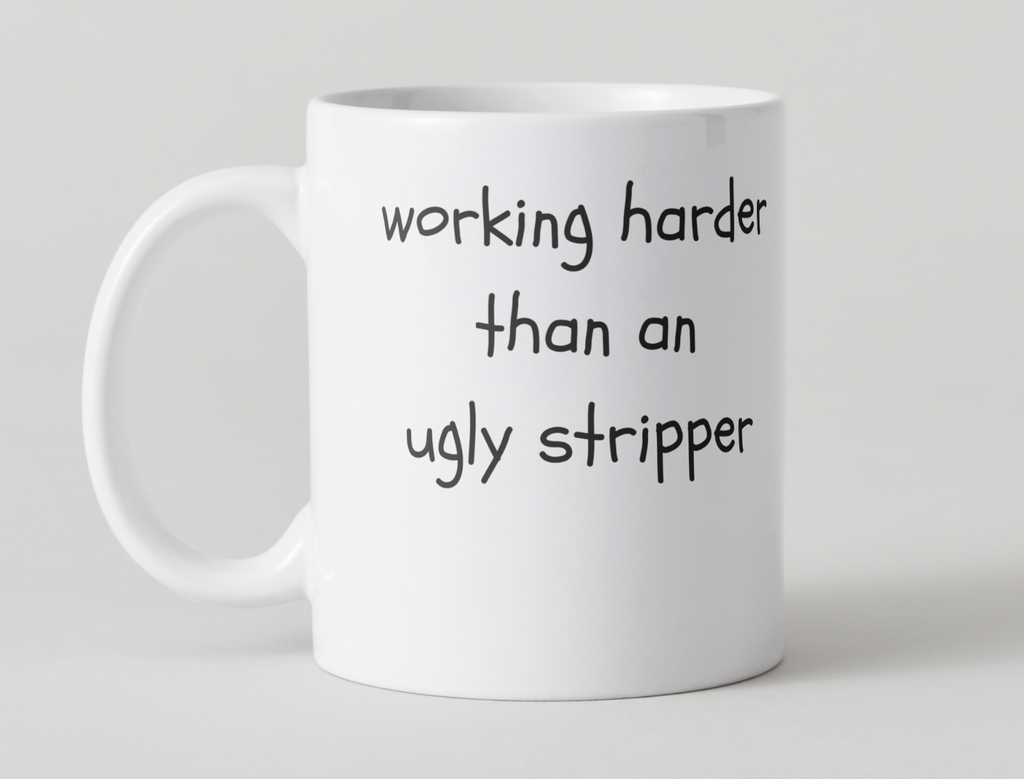 White mug with black 'Working harder than an ugly stripper' design on a light gray 