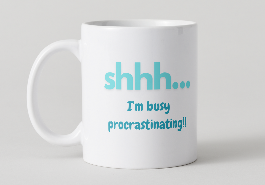 White mug with blue text 'shhh... I'm busy procrastinating!' on a light gray background